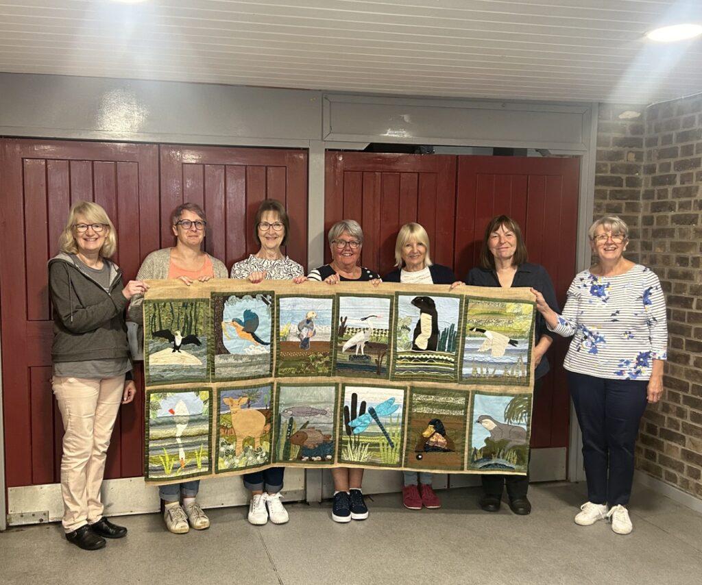 Guildhall Craft Group holding a tapestry depicting local wildlife